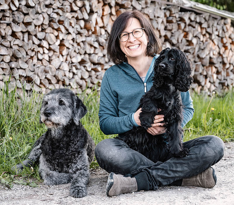 hundeschule-susanne-kohler-bühlerzell - susanne kohler läuft lachend mit ihren beiden hunden über ein feld vor dem abendhimmel 